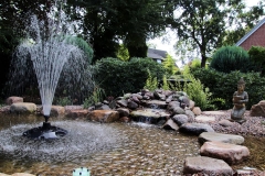 Blick auf Bachlauf, Springbrunnen und Trittsteine im Teich